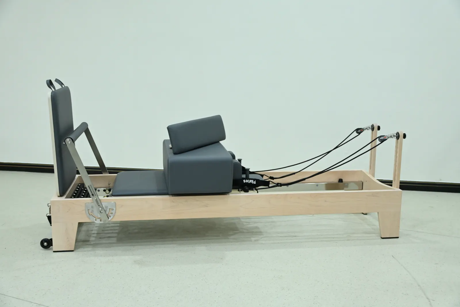 Wood-frame Pilates reformer shown from the side